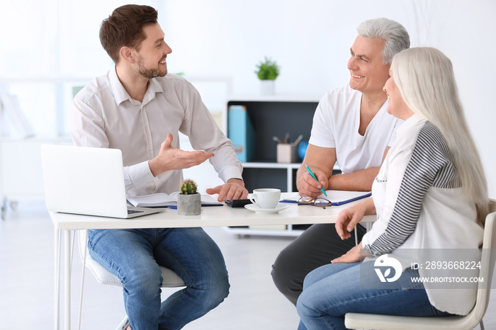 Mature couple discussing pension plan with consultant in office