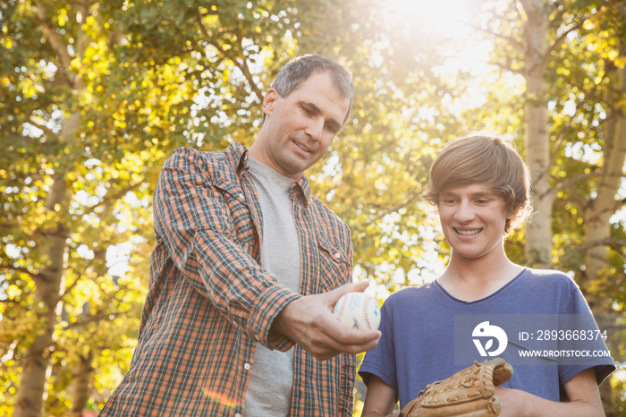 Father showing baseball grip to son at park