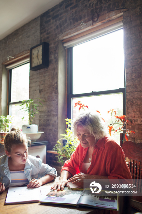 Grandmother doing homework with girl (6-7)