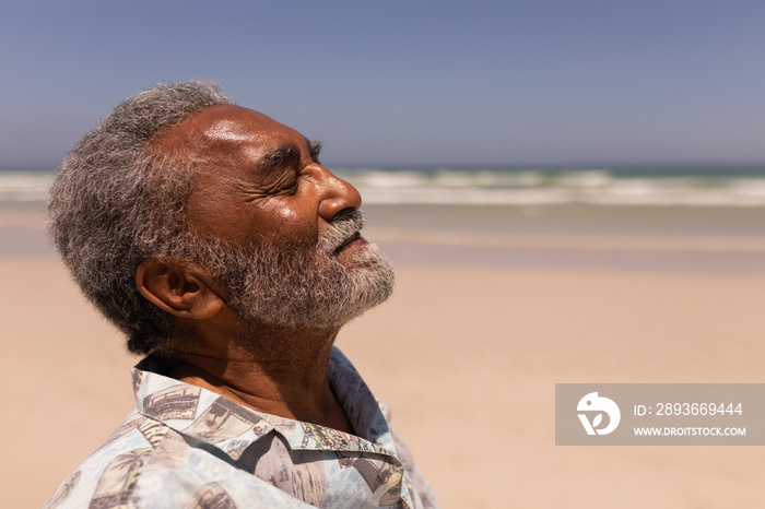 Senior black man with eyes closed standing on beach