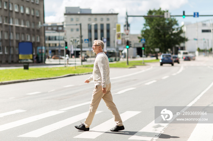 senior man walking along city crosswalk