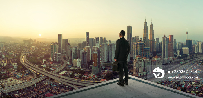 Businessman stand at rooftop looking great cityscape view and thinking business plan of the future .