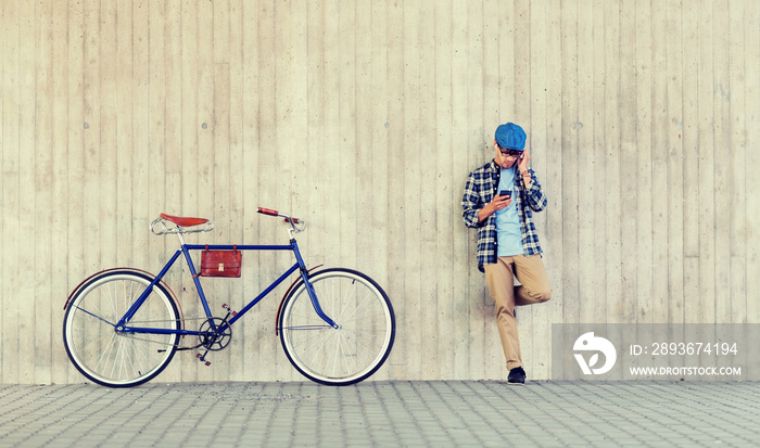 people, style, technology, leisure and lifestyle - young hipster man in earphones with smartphone an