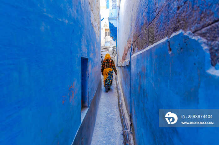 Indian women in traditonal india dressed Indian Saree walking through the narrow blue streets of the