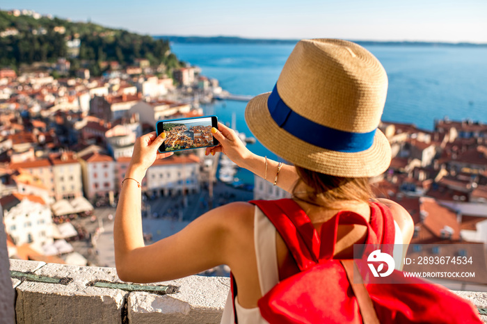 Young female traveler with red backpack and photo camera enjoying the view on Piran old town. Travel