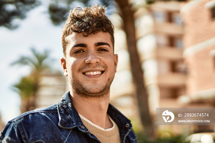 年轻的西班牙男子站在城市里开心地微笑