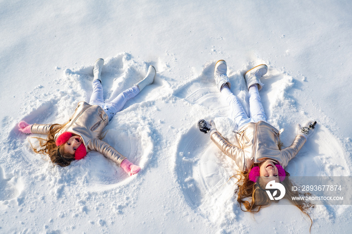 两个小女孩躺在雪地上做雪天使。雪天使上的快乐女孩秀。