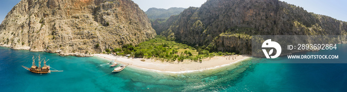 远离空中的海滩，四周是陡峭的山谷和碧绿的海水，还有帆船。