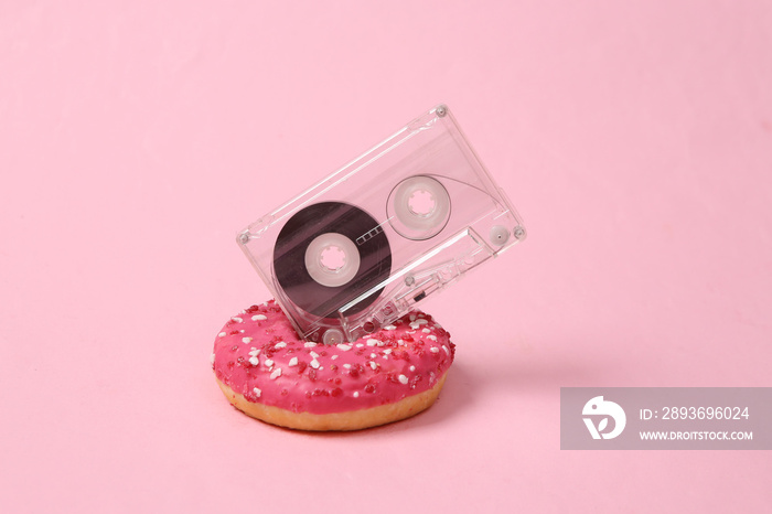 Donut with audio cassette on a pink background. Minimalism. Concept art