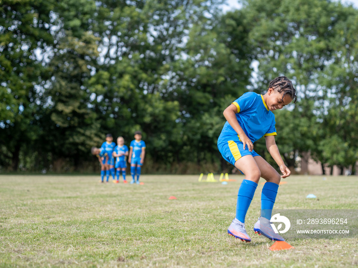 身着制服的儿童（8-9岁）在足球场上练习