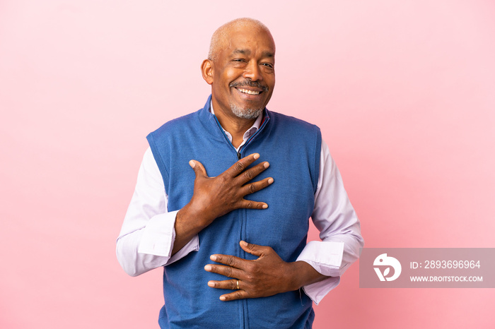 Cuban senior isolated on pink background smiling a lot