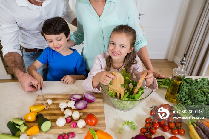Kids and parents preparing vegetable salad in kitchen