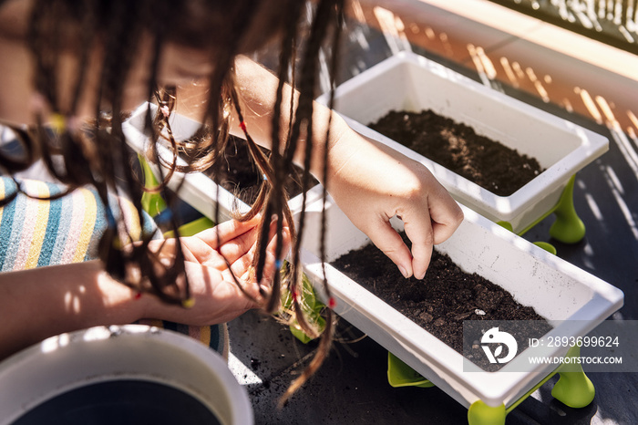 girl putting seeds in the dirt of the flower pots