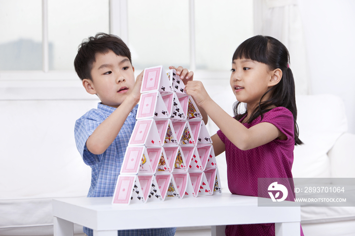 男孩和女孩玩搭建纸牌游戏