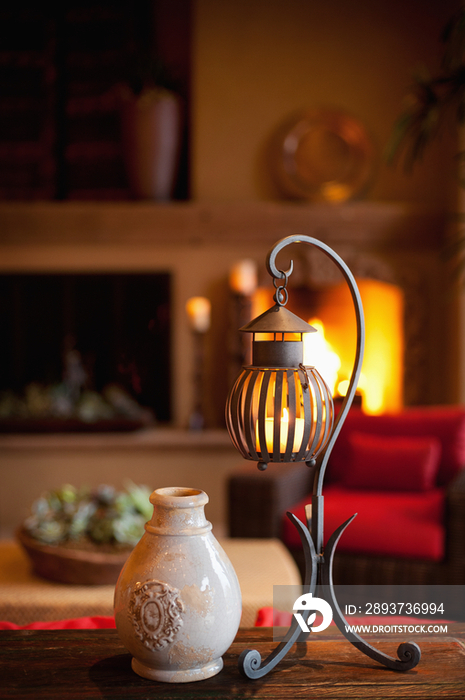 Pot with candle lantern on table against lit fireplace in living room at home; Scottsdale; USA