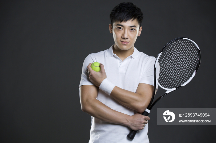 年轻男子拿着网球和球拍