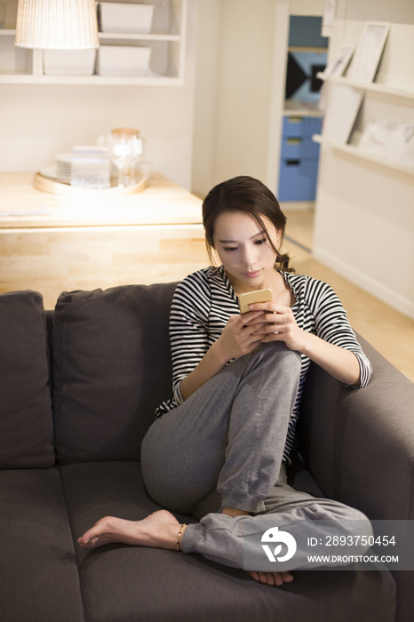 年轻女子在客厅沙发上使用手机