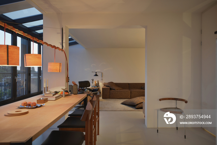 Lit lamps over dining table with living room in the background at modern house