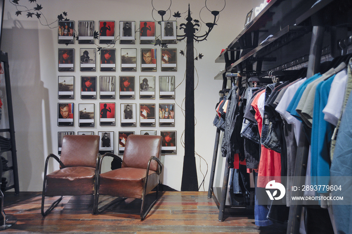 Leather armchairs by clothing rack in store