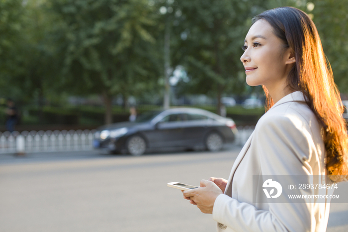 年轻女子拿着手机等出租车