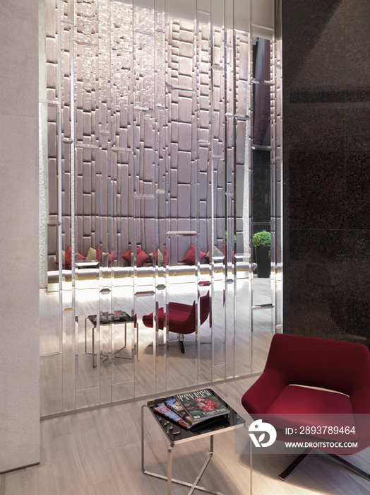 Modern red chair and table by patterned glass wall in house