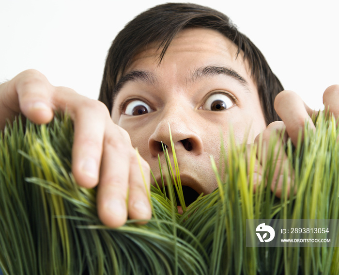 Surprised man behind grass.