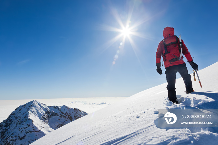 在一个阳光明媚的冬天，一位登山者登上了一座雪山的山顶