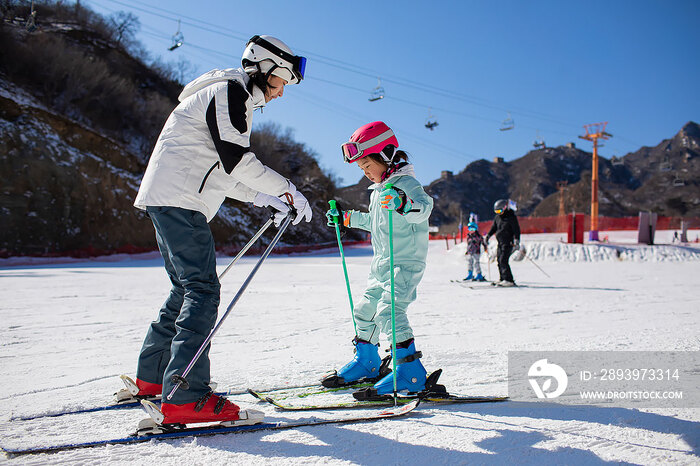 小女孩跟着教练在户外学滑雪