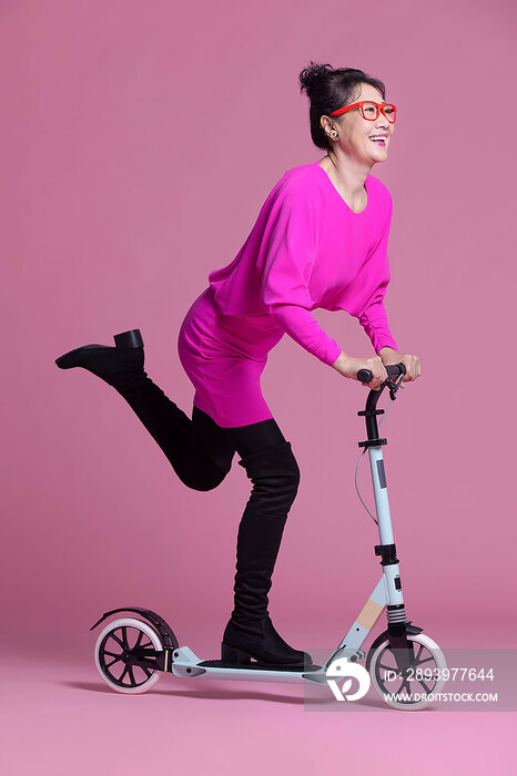 幽默时尚的老年女子骑滑板车