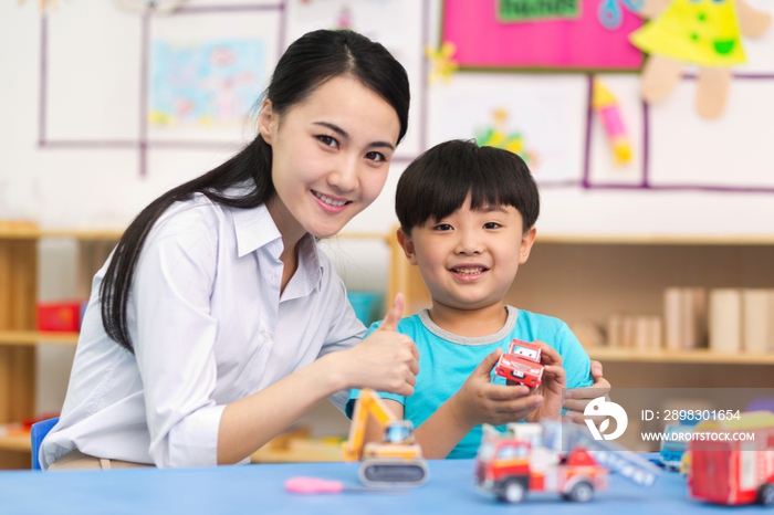 幼儿园女老师和儿童一起玩小汽车玩具