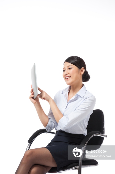 棚拍年轻商务女士坐在办公椅上使用平板电脑