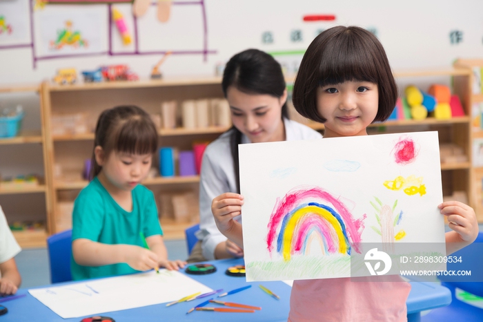 幼儿园女老师和儿童展示绘画作品