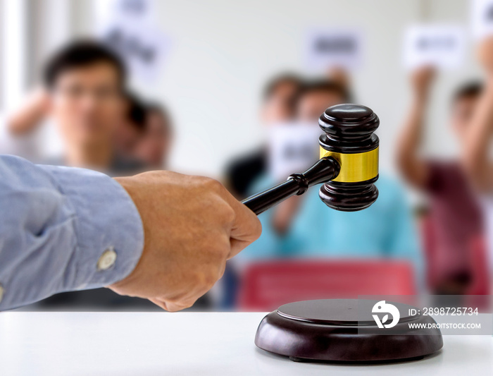 The person carrying the auction holds a wooden hammer in his hand to make a bid to sell the product.