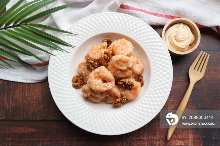 Honey Walnuts Shrimp - Chinese crispy shrimp with creamy sweet sauce topped with caramelized walnuts in white plate - Top view on the wooden table ( Koong Tod cream salad in Thai language)