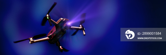 Flying drone with camera on dark blue background with copy space. Airborne quadcopter. Also known as a drone or UAV, Unmanned Aerial Vehicle. Low angle view.