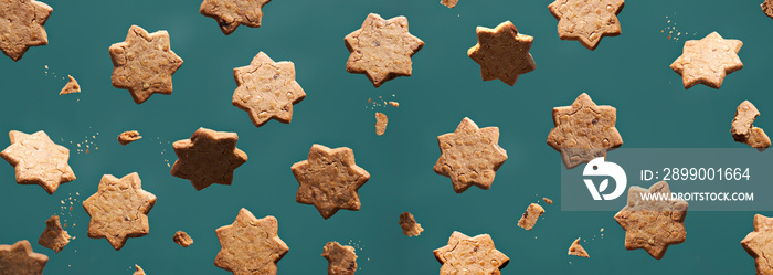 Levitation of star cookies, panoramic banner. Yellow, green and beige, muted wintertime colors. Star shaped cinnamon cookies levitating on emerald green background. Abstract panorama, creative food