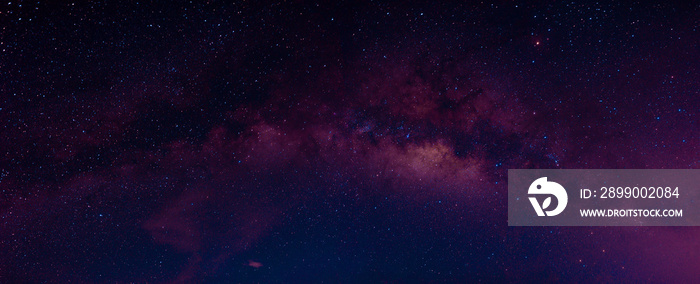 Milky way in the night sky and stars on dark background with noise and grain. Photo taken with long exposure and white balance selected.