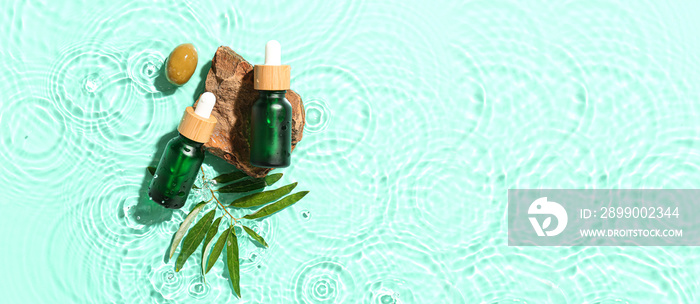 Bottles of essential olive oil in water on turquoise background