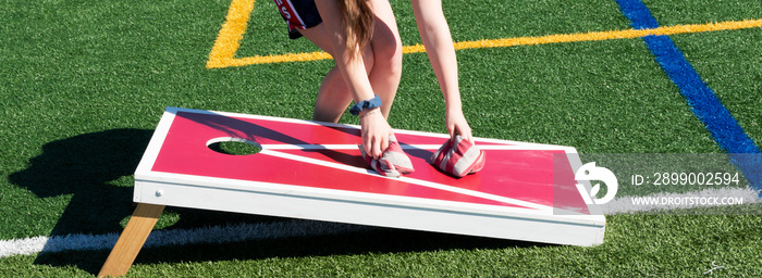 Girl picking up bean bags from cornhole game board