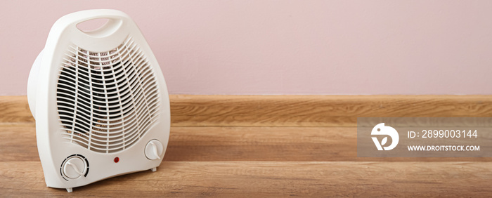 Electric fan heater on floor near pink wall. Banner for design