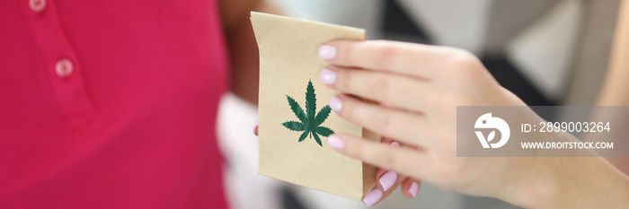 Woman hand passes paper bag with and marijuana closeup