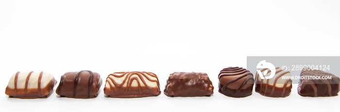 Fine brown white chocolate pralines on a single row  isolated on white background.