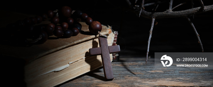 Close up rosary, ancient Bible and thorn wreath as symbol of death and resurrection of Jesus Christ. Horizontal image.