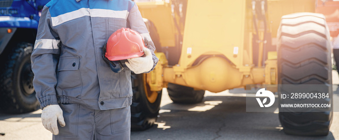 Concept of job placement for drivers of construction equipment. Banner industrial man holding hard hat on background of excavator