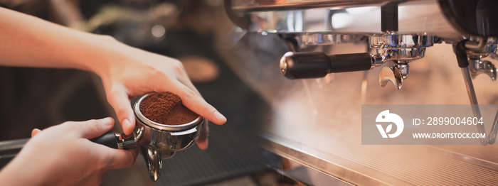 Close up of a hand holding a filter holder with ground coffee and espresso machine or coffee machine with stream and smoke.  Concept of modern warm coffee shop and Preparing process of coffee Banner.