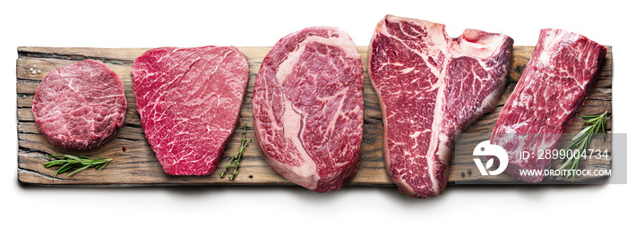 Different raw beef steaks on the wooden board on white background. Top view.