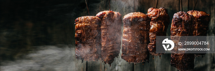 Composition of meats. Traditionally smoked ham. Hanging ham in the smokehouse smoked bacon for smoking. Long banner format