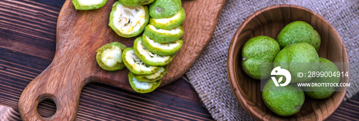 Cut into slices lying on cutting wooden vintage board ingredients for tincture of green walnuts in a wooden ecological plate without chemicals. zero waste. Still life of nuts, wooden utensils