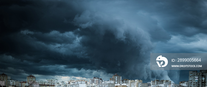 Dramatic stormy clouds over residential buildings. Panorama of the city with dark and powerful clouds.