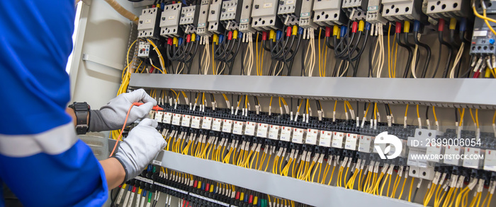 Electricity and electrical maintenance service, Engineer hand holding AC voltmeter checking electric current voltage at circuit breaker terminal and cable wiring main power distribution board.